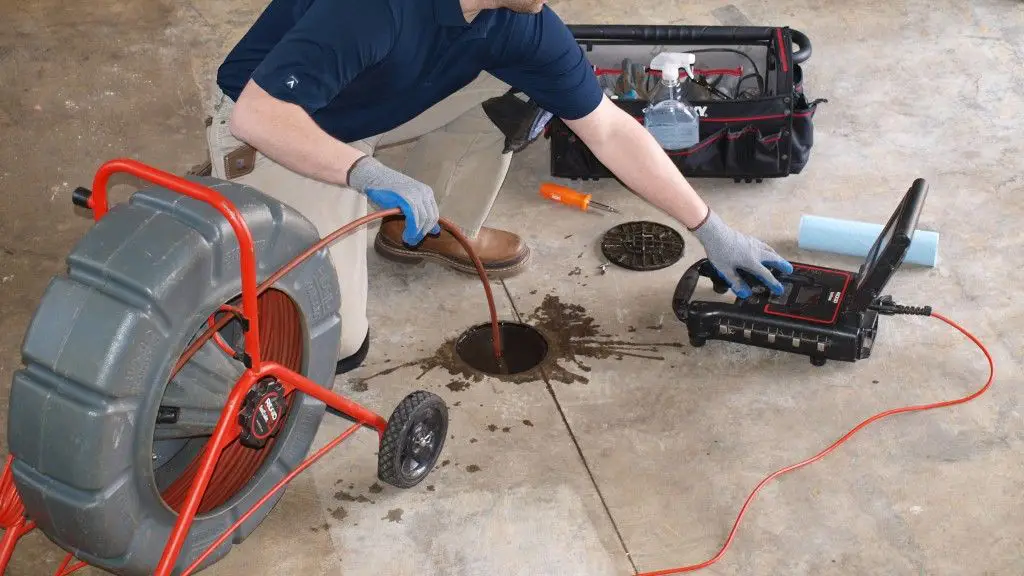 Technician performing a sewer camera inspection through a floor drain - xtraPro