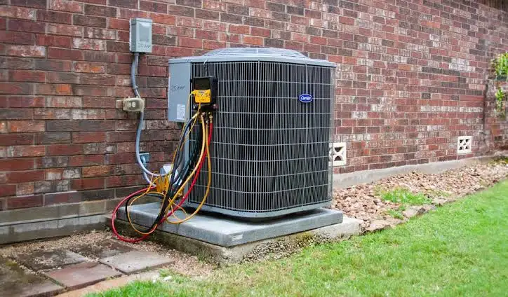 Outdoor air conditioning unit installed beside a brick house.